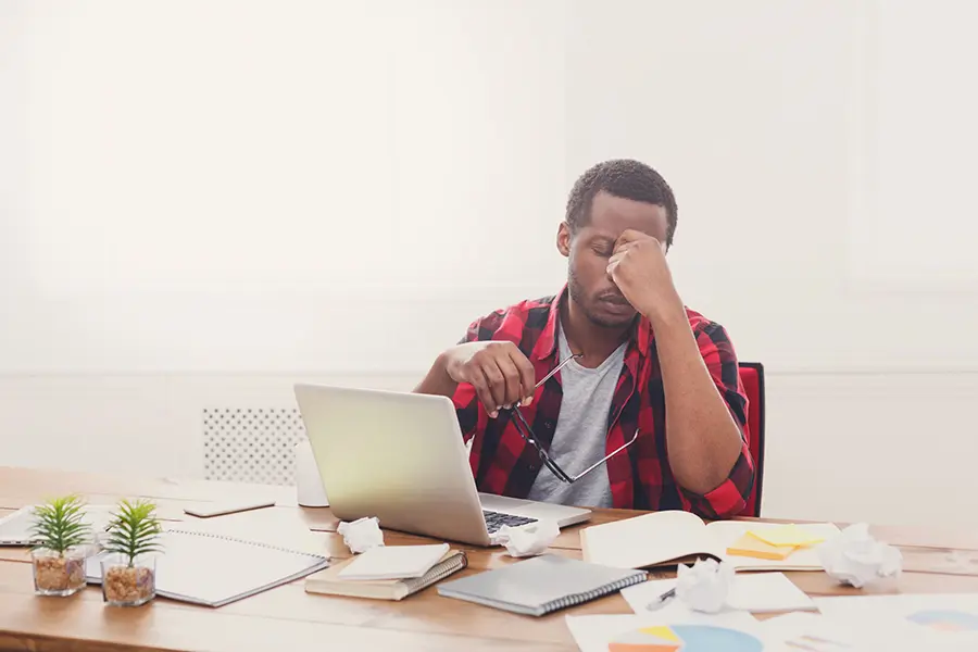 Frustrated man at laptop struggling with presentation design, learning to avoid common mistakes using AI tools like hiCreo