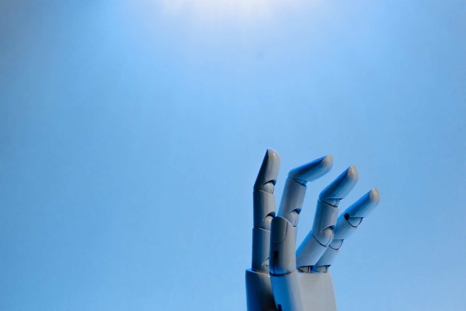 Revolutionize eLearning with hiCreo - white robot hand reaching towards the sky on blue background.
