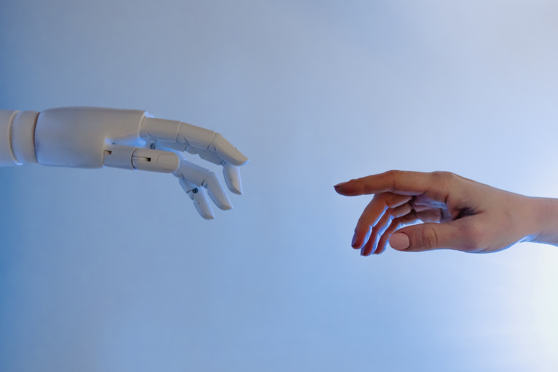 Experience the power of hiCreo's AI in elearning - human and robotic hands about to touch