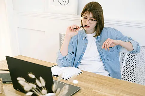 Thoughtful woman working on a laptop, using an AI presentation maker to create presentations with AI and professional presentation templates.