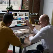 Two professionals collaborating on a computer screen displaying hiCreo.ai, the AI-powered presentation software, in a modern office setting.