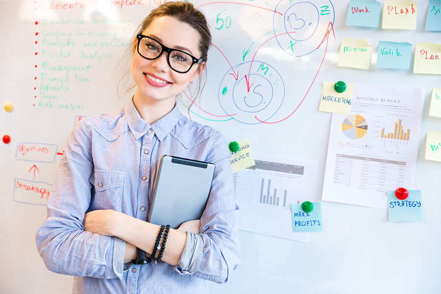 Smiling young woman using hiCreo.ai to create a compelling presentation on a whiteboard with graphs and charts.